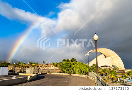 Scenic view of a beautiful rainbow over the iconic white curves of the Auditorio de Tenerife and palm trees in Santa Cruz de Tenerife, Canary Islands. 137173150