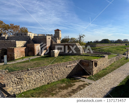 Historic fortress tower behind brick wall under blue sky in Belgrade. Heritage, architecture and cultural preservation in urban environment. 137173457