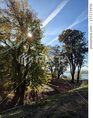 City skyline and trees above the river in autumn sunlight. Balance between urban architecture and calm natural landscape. City skyline and trees above the river in autumn sunlight. Balance between urban architecture and calm natural landscape. 137173458