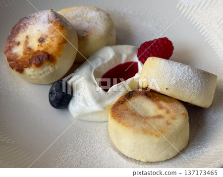 Cheesecakes with berries and cream on white plate close-up. Dessert harmony, delicate sweetness, and cozy cafe indulgence. 137173465