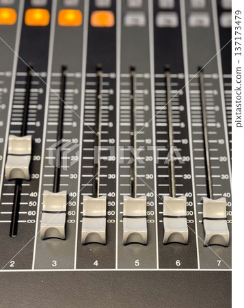 Audio mixing console with sliders and illuminated buttons close-up. Sound engineering, music production and professional recording technology for creative audio control. 137173479