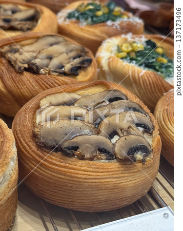 Freshly baked pastries with mushrooms and vegetables in bakery display close-up. Savory flavors, texture, and craftsmanship in gourmet patisserie. Freshly baked pastries with mushrooms and vegetables in bakery display close-up. Savory flavors, texture, and craftsmanship in gourmet patisserie. 137173496