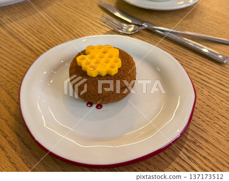 Round dessert with honeycomb decoration placed on white plate close-up. Sweet bakery item presenting texture, craft, and culinary detail. Round dessert with honeycomb decoration placed on white plate close-up. Sweet bakery item presenting texture, craft, and culinary detail. 137173512