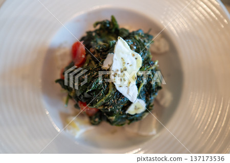 Traditional greek dish of boiled leafy greens served with tomatoes and fresh white cheese in a white plate Traditional greek dish of boiled leafy greens served with tomatoes and fresh white cheese in a white plate 137173536