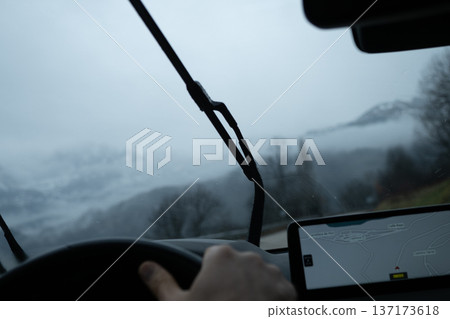 Car dashboard and windshield wipers active while navigating a mountain route in heavy fog and rainy weather Car dashboard and windshield wipers active while navigating a mountain route in heavy fog and rainy weather 137173618