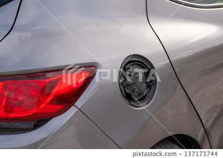 Rear view of a gray car showing a missing or broken fuel tank door cover 137173744