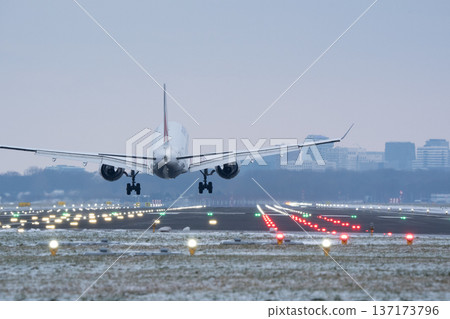 Commercial airliner about to touch down on a snowy landing strip with bright signal lights Commercial airliner about to touch down on a snowy landing strip with bright signal lights 137173796
