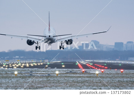 Large commercial airplane approaching a winter airport runway with landing lights at twilight Large commercial airplane approaching a winter airport runway with landing lights at twilight 137173802