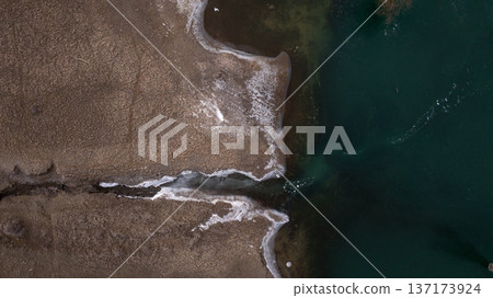 Aerial perspective of an icy water channel cutting through brown winter terrain Aerial perspective of an icy water channel cutting through brown winter terrain 137173924