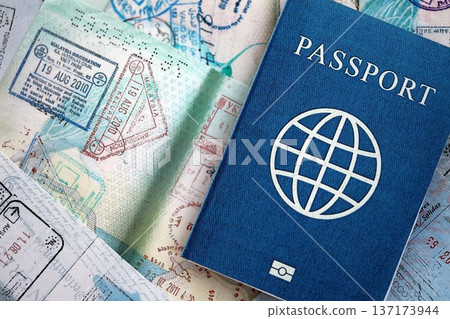 One fictional passport on big amount of passport pages full of colorful stamps after travel and border crossing. Tourism and border control concept. Immigration and travel around the world 137173944