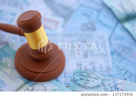 Judgement gavel on passport pages full of colorful stamps after travel and tourism. Border control and lawsuit concept. Immigration and travel around the world Judgement gavel on passport pages full of colorful stamps after travel and tourism. Border control and lawsuit concept. Immigration and travel around the world 137173956
