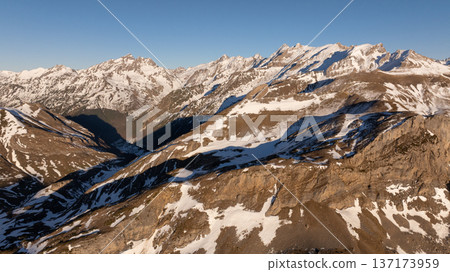 Aerial perspective of multiple mountain ridges showing geological layers and winter snow 137173959