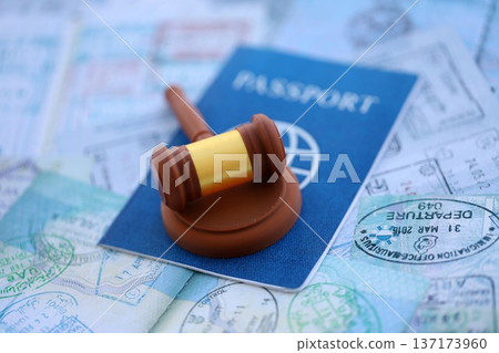 Judgement gavel on passport pages full of colorful stamps after travel and tourism. Border control and lawsuit concept. Immigration and travel around the world 137173960