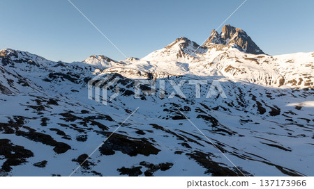 High altitude view of white snow fields leading to a distinctive rocky mountain peak 137173966