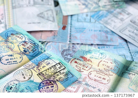 Big amount of passport pages full of colorful stamps after travel and border crossing. Tourism and border control concept. Immigration and travel around the world Big amount of passport pages full of colorful stamps after travel and border crossing. Tourism and border control concept. Immigration and travel around the world 137173967