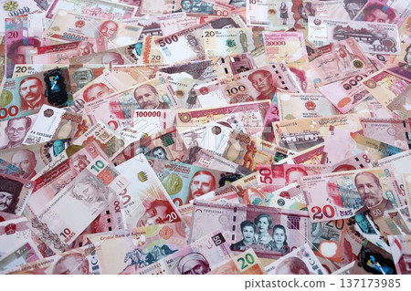 Various currencies money bills banknotes in red color. Many cash bills from different countries in big pile close up. World economy and currency exchange concept 137173985
