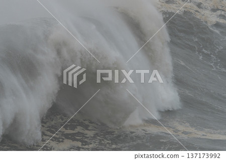 Extreme close up of a massive wall of water and sea foam crashing down in the stormy atlantic ocean Extreme close up of a massive wall of water and sea foam crashing down in the stormy atlantic ocean 137173992