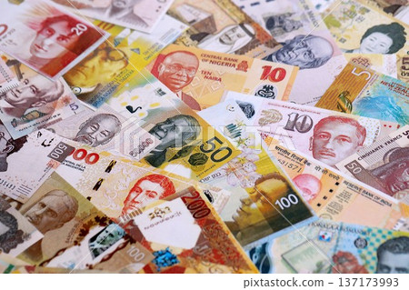 Various currencies money bills banknotes in yellow and orange color. Many cash bills from different countries in big pile close up. World economy and currency exchange concept Various currencies money bills banknotes in yellow and orange color. Many cash bills from different countries in big pile close up. World economy and currency exchange concept 137173993