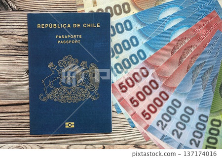 Chile Republic passport lies on wooden table with chilean pesos money bills close up. Chilean blue new passport book in details Chile Republic passport lies on wooden table with chilean pesos money bills close up. Chilean blue new passport book in details 137174016