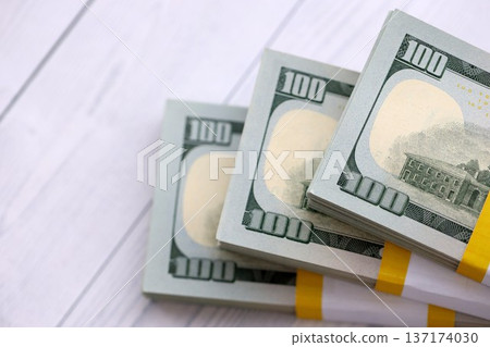 Three packs of ten thousand US dollar bills on wooden background. Packs of hundred dollar bills in stack on white wood planks close up Three packs of ten thousand US dollar bills on wooden background. Packs of hundred dollar bills in stack on white wood planks close up 137174030