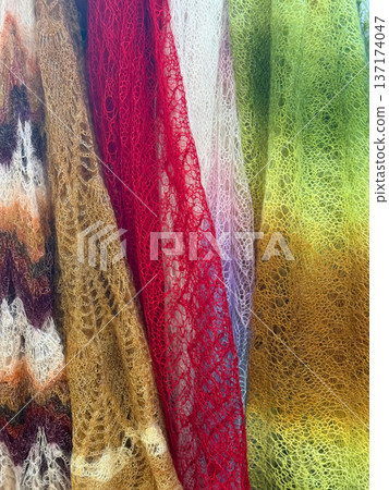 Colorful knitted mohair drapery with lace pattern texture in multicolor tones, vertical folds. Natural woolen background, fashion knitted fabric texture, craft textile design Colorful knitted mohair drapery with lace pattern texture in multicolor tones, vertical folds. Natural woolen background, fashion knitted fabric texture, craft textile design 137174047