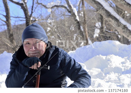 An elderly man taking a break from rehabilitation using a cane in a snowy country An elderly man taking a break from rehabilitation using a cane in a snowy country 137174180