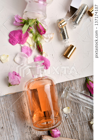 perfume empty bottles and essence around roses settled at authentic provence background. Perfumer, beauty and trendy concept. flat lay perfume empty bottles and essence around roses settled at authentic provence background. Perfumer, beauty and trendy concept. flat lay 137174187