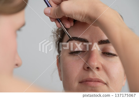 Caucasian woman getting eyebrow tinting procedure. Caucasian woman getting eyebrow tinting procedure. 137175067