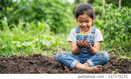 Little girl carefully and lovingly holding a small plant 137175255