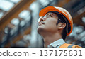 A young male worker looking up at a construction site 137175631