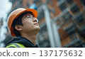 A young male worker looking up at a construction site 137175632