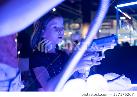 Girl playing laser tag shooting game in neon lit 137176267