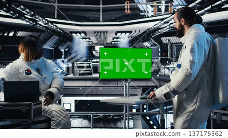Astronauts fly together in starship, looking at isolated screen monitor, gathering samples for study. Scientists using chroma key display before landing on red planet Astronauts fly together in starship, looking at isolated screen monitor, gathering samples for study. Scientists using chroma key display before landing on red planet 137176562