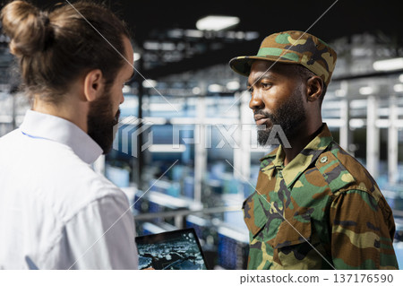 Diverse military personnel overseeing AI cloud computing operations on laptop in national server farm. Army experts using artificial intelligence to oversee threat detection defense systems. Diverse military personnel overseeing AI cloud computing operations on laptop in national server farm. Army experts using artificial intelligence to oversee threat detection defense systems. 137176590