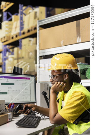 Exhausted female staff with helmet falling asleep scanning barcodes at desk, working on registering shipping labels and feeling overworked in the warehouse. Deals with burnout on the job. Exhausted female staff with helmet falling asleep scanning barcodes at desk, working on registering shipping labels and feeling overworked in the warehouse. Deals with burnout on the job. 137176594