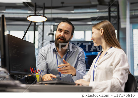 Senior technician mentoring young girl at workstation in startup office, reviewing code scripts. Tech company experienced manager guiding intern doing software development Senior technician mentoring young girl at workstation in startup office, reviewing code scripts. Tech company experienced manager guiding intern doing software development 137176610