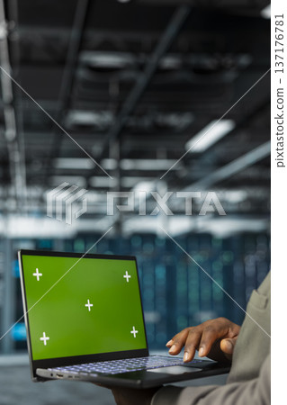 Close up of technician using green screen laptop in data center, managing rackmounts systems. Server hub employee using mockup notebook, installing upgraded infrastructure 137176781