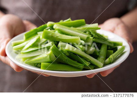 Hand holding a white plate with sliced Chinese kale or Chinese broccoli (Gai Lan) Hand holding a white plate with sliced Chinese kale or Chinese broccoli (Gai Lan) 137177076