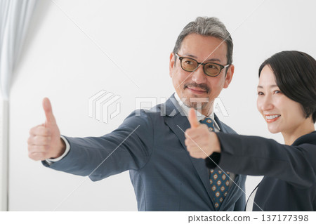 Men and women in suits smiling and showing thumbs up Men and women in suits smiling and showing thumbs up 137177398