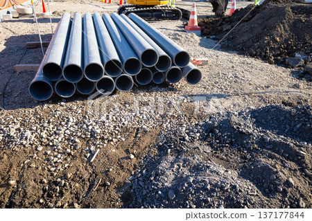 Construction site: Piping materials and excavator a-1 Construction site: Piping materials and excavator a-1 137177844