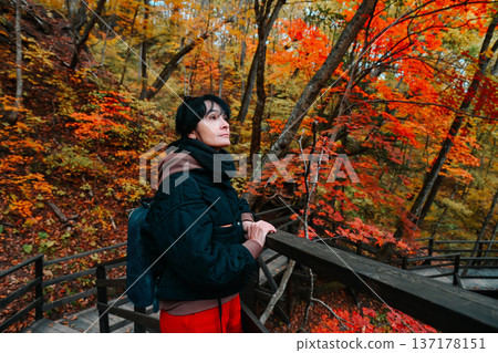 Russian woman 50 years old solo traveler looking into distance at autumn leaves on forest stairs Far East Russia reflecting inner calm and wellness Russian woman 50 years old solo traveler looking into distance at autumn leaves on forest stairs Far East Russia reflecting inner calm and wellness 137178151