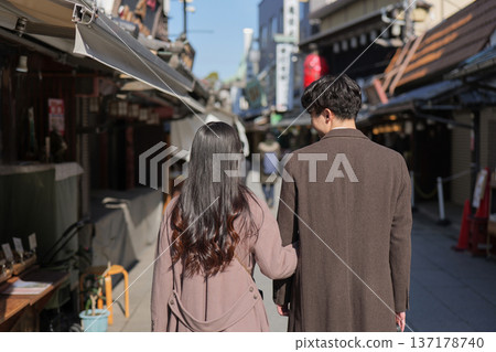 Back view of a couple walking arm in arm through a tourist spot in Shibamata 137178740