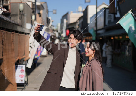 A smiling couple taking a selfie at a tourist spot in Shibamata 137178756