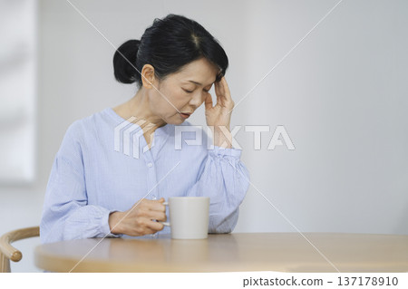 A woman in her late 50s holding her head A woman in her late 50s holding her head 137178910