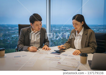 two business colleagues meeting and discussing financial reports and using calculator to data analysis in office at night two business colleagues meeting and discussing financial reports and using calculator to data analysis in office at night 137179138