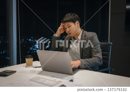 stressed businessman headache while working on laptop computer in business office with city lights background at night 137179182