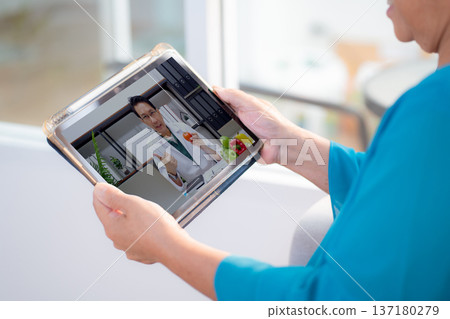 Senior asian woman using tablet for online consultation with nutritionist at home. Senior asian woman using tablet for online consultation with nutritionist at home. 137180279