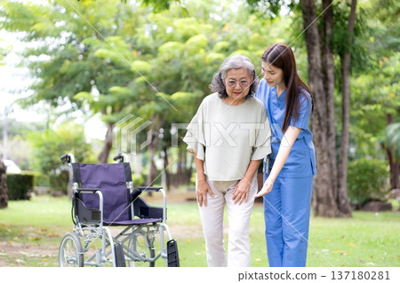 Asian female caregiver helping senior patient walking for physical rehabilitation. Asian female caregiver helping senior patient walking for physical rehabilitation. 137180281