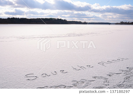 Written SAVE THE PLANET on snow background message ice outdoor on ground in winter. Writing text sign drawing on field in frozen background. Weather changing cold season has arrived environment Written SAVE THE PLANET on snow background message ice outdoor on ground in winter. Writing text sign drawing on field in frozen background. Weather changing cold season has arrived environment 137180297