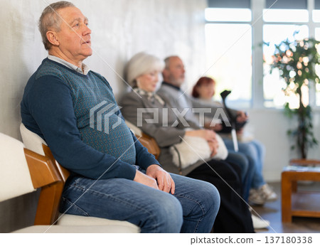 Group of elderly people sitting in chairs in queue to see doctor in lobby medical facility 137180338